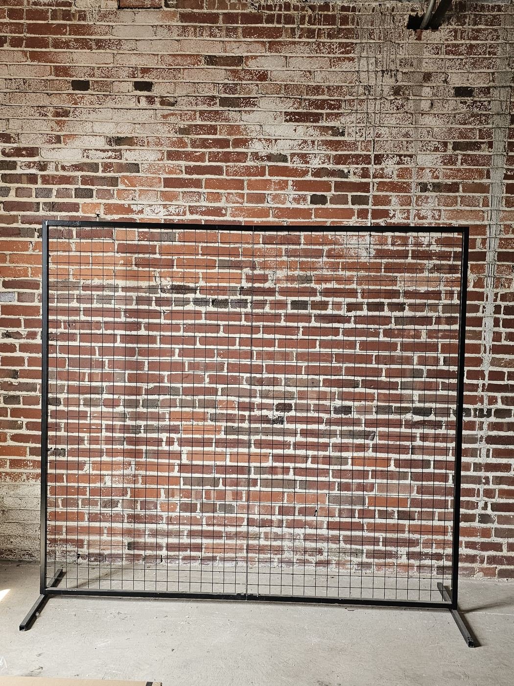 Black square wedding backdrop frame against a brick wall