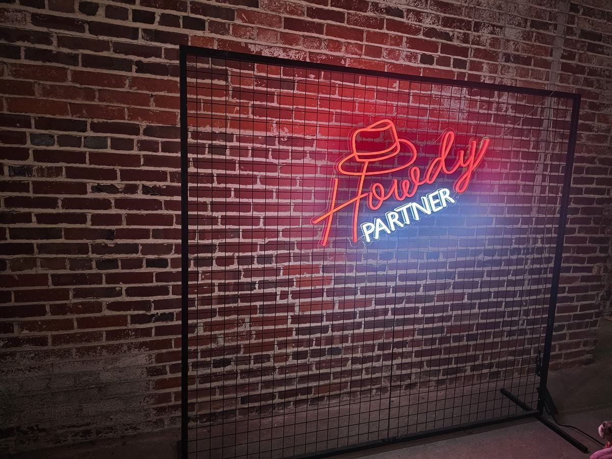 Howdy Partner neon sign on a black square backdrop