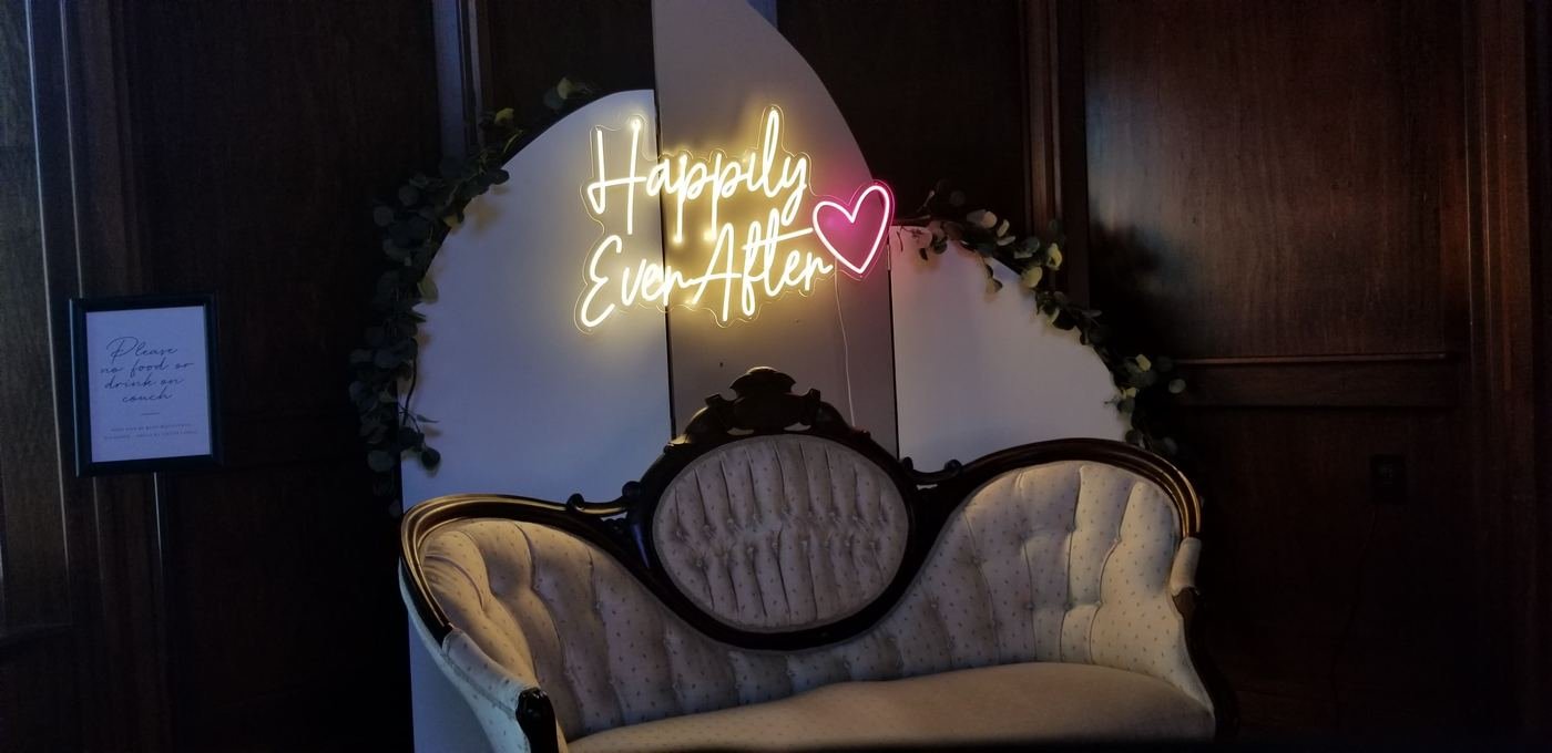 Happily Ever After neon sign styled behind a vintage loveseat at an Indiana reception